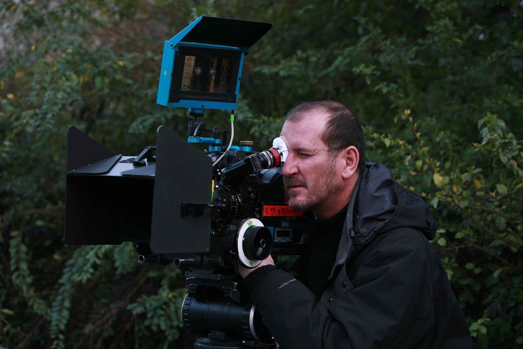 Camera operator looking through a cinema camera viewfinder on an outdoor shoot
