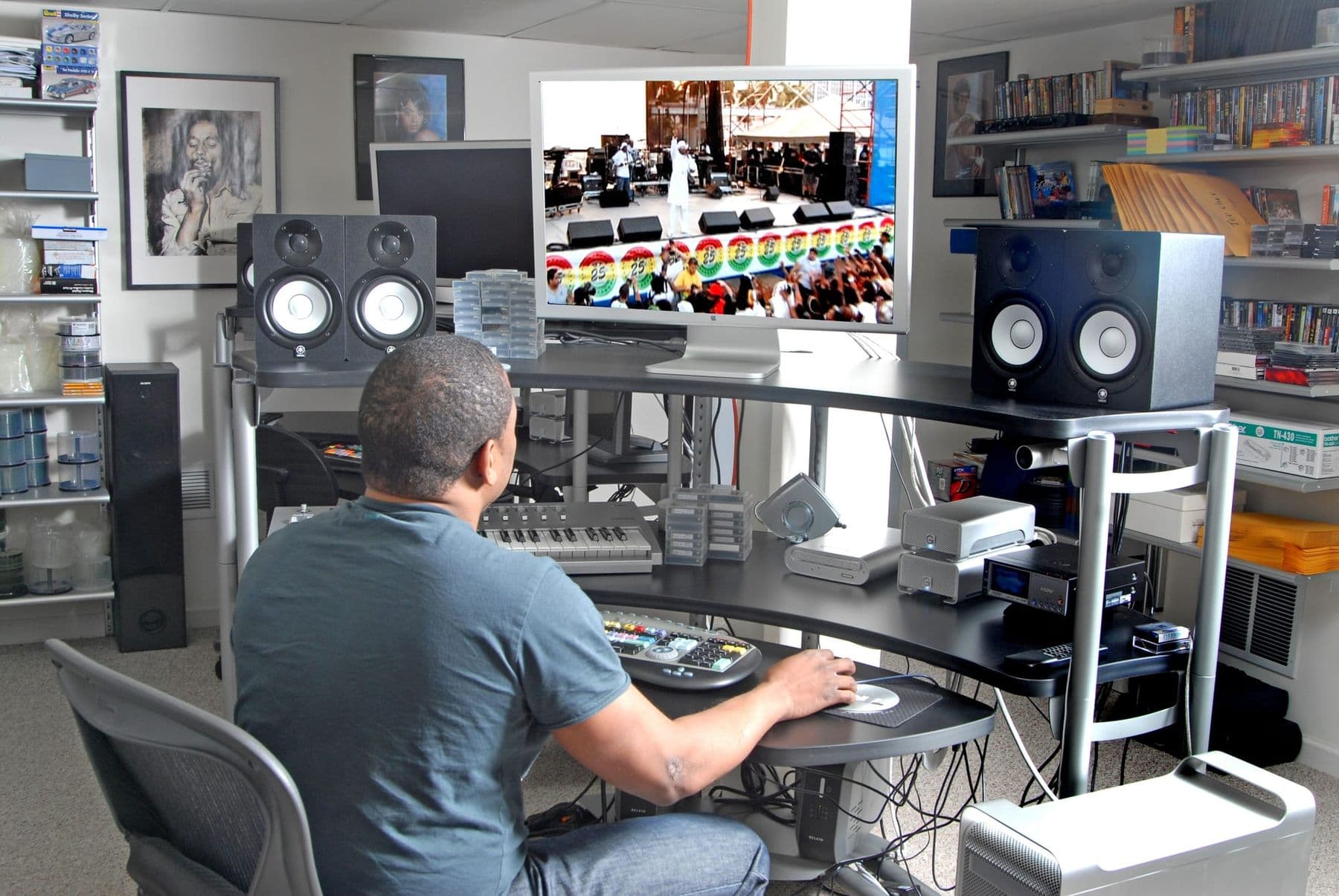 Editor at an editing desk with studio monitor speakers and a large screen