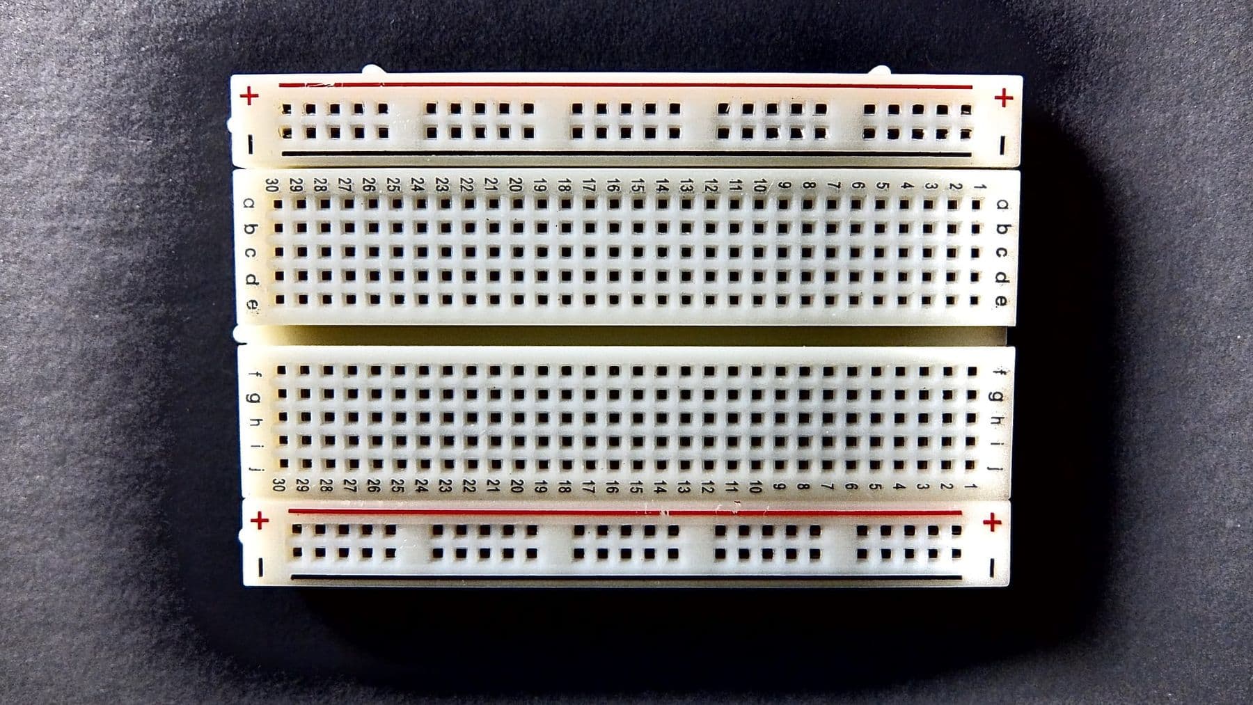ცარიელი breadboard ზემოდან: კვების ზოლები პლიუსით და მინუსით, შუაში ღარი
