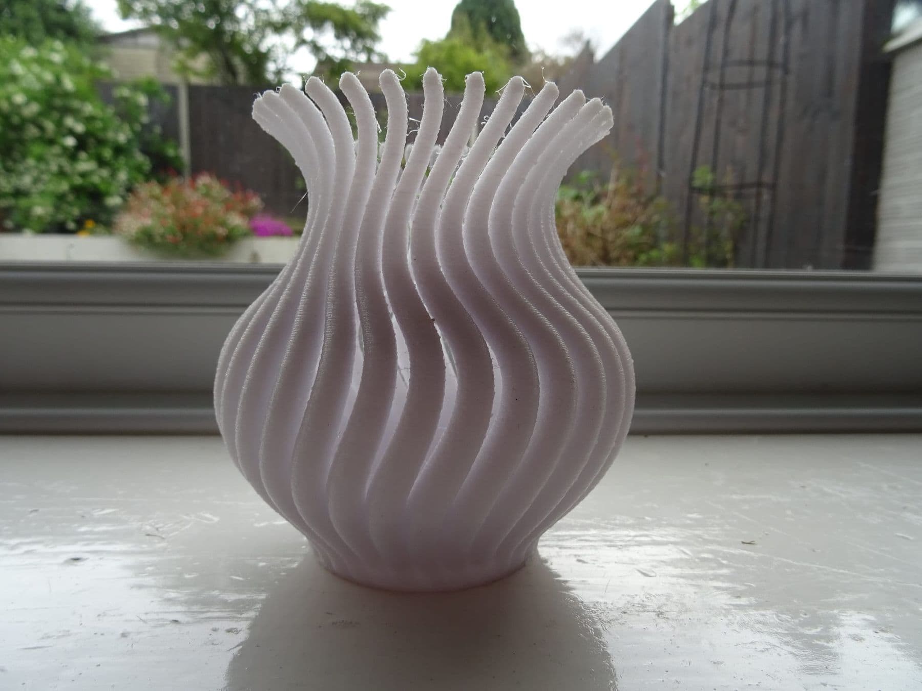 White twisted vase printed on a 3D printer, by a window