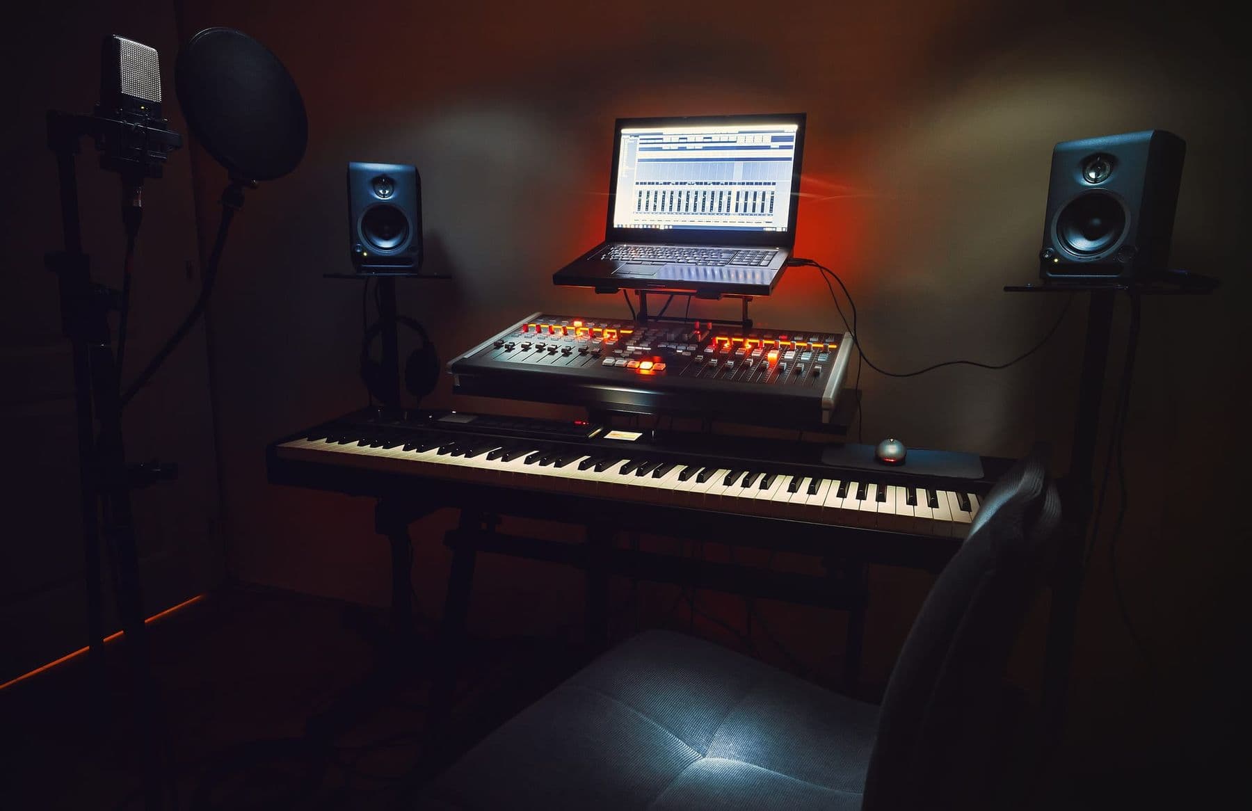 A small home studio with a microphone, keyboard, speakers and laptop for voice and music