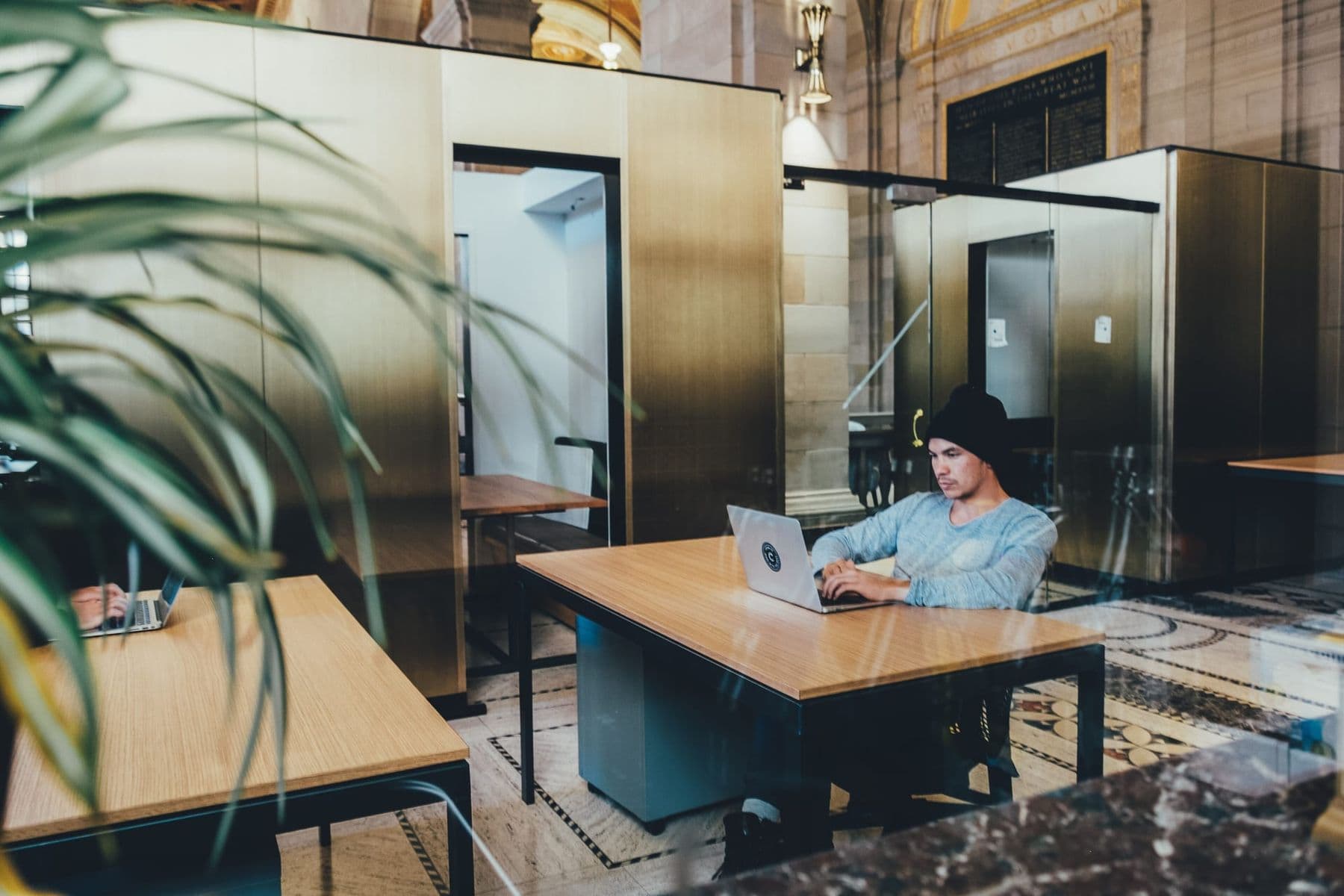 A young man works on a laptop at a desk in an open office space