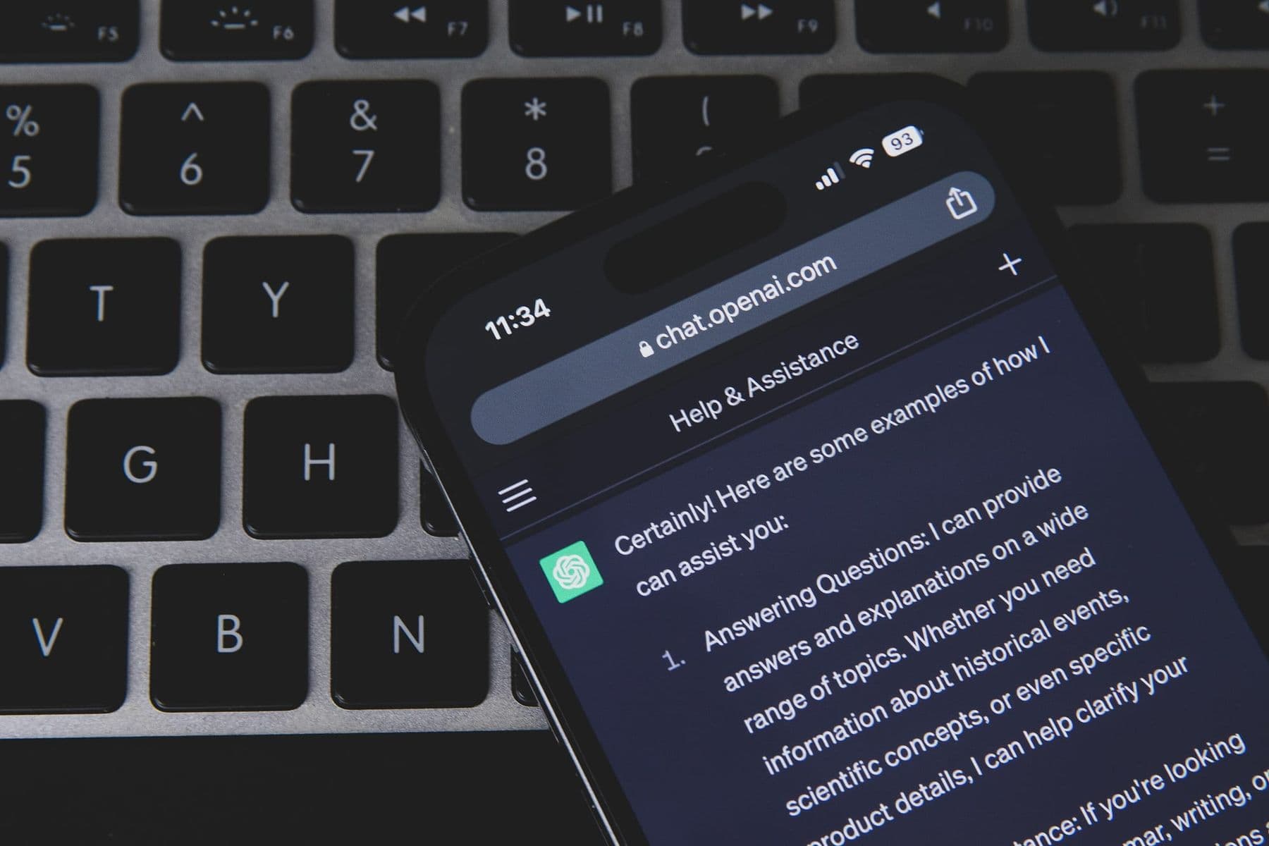 A smartphone showing a ChatGPT chat lying on a laptop keyboard