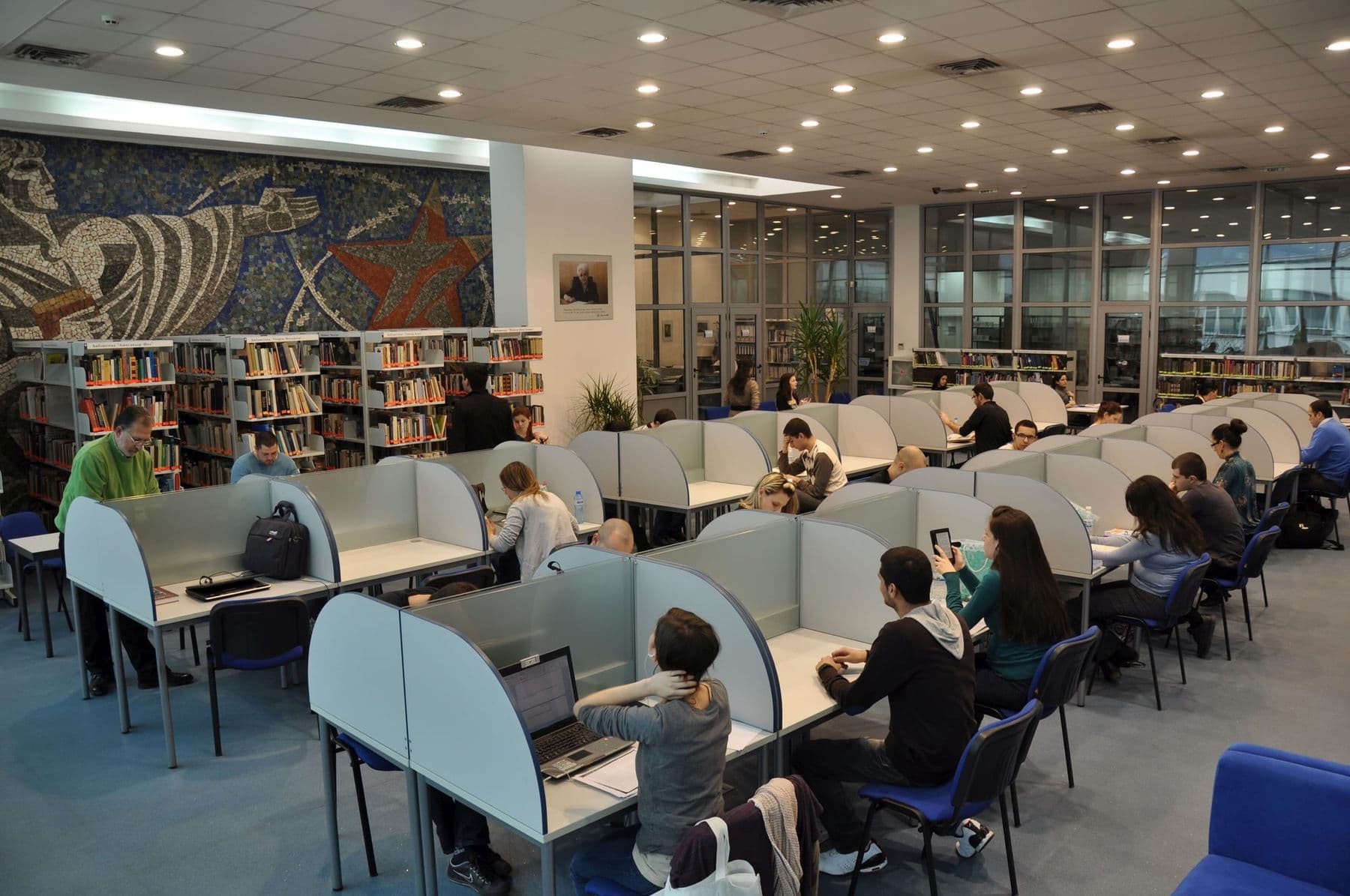 Students working on laptops in a university library reading room