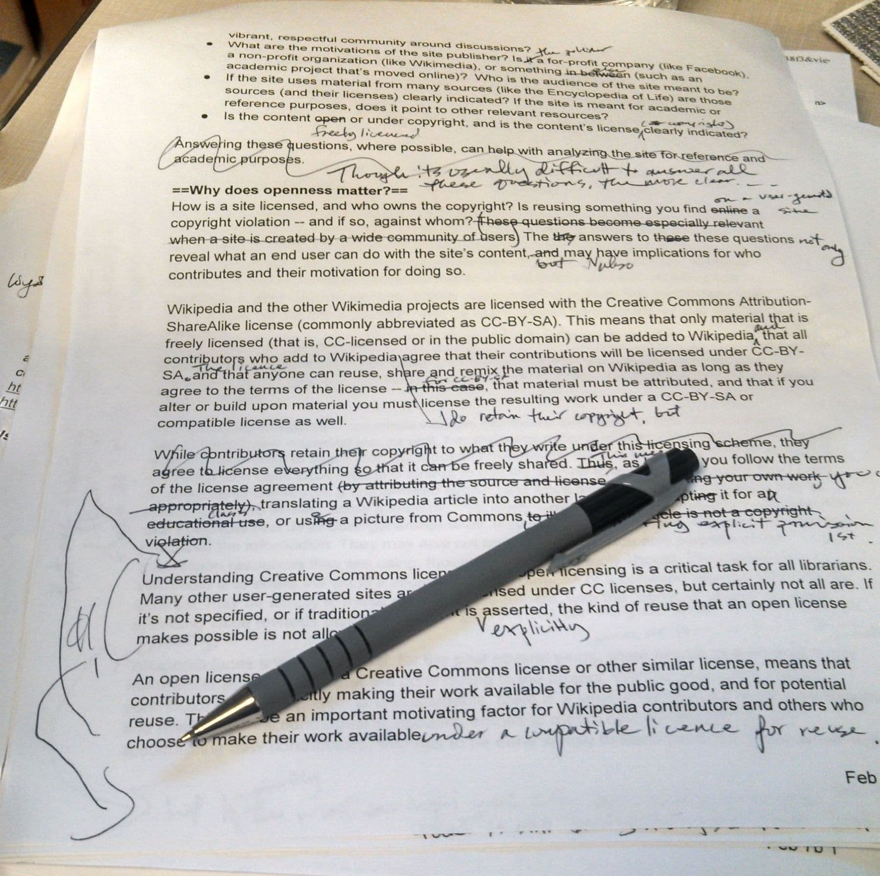 Printed essay covered with handwritten corrections and a pen, written feedback