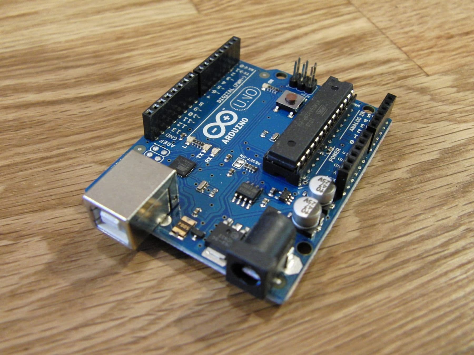 არდუინო უნო (Arduino Uno) დაფა ხის მაგიდაზე, USB და კვების ბუდით