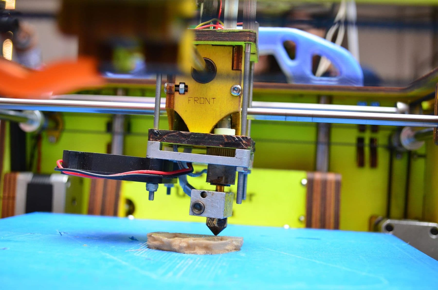 3D printer nozzle laying down plastic layers on the build plate