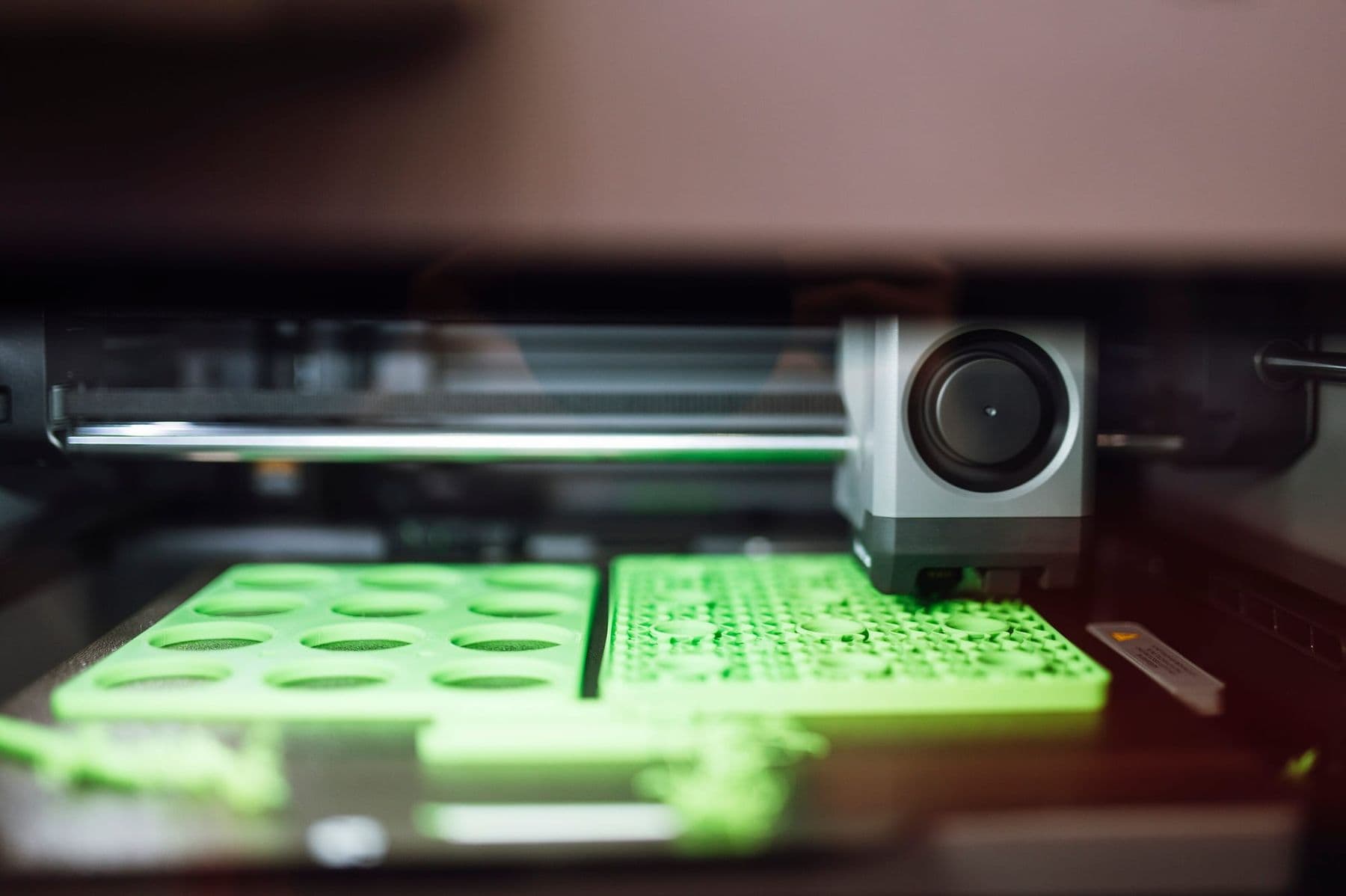 3D printer printing green PLA parts on the build plate