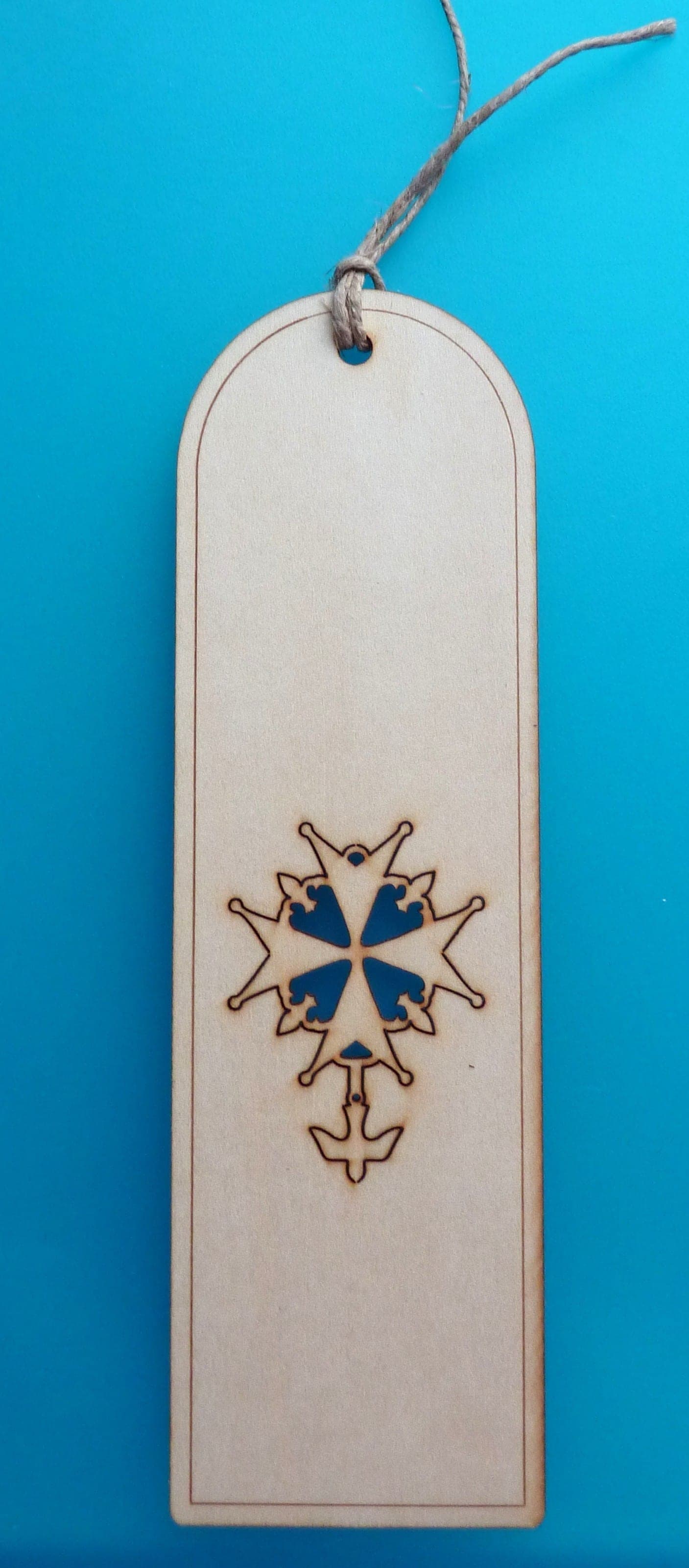 A linden wood bookmark with a laser-engraved and coloured cross motif