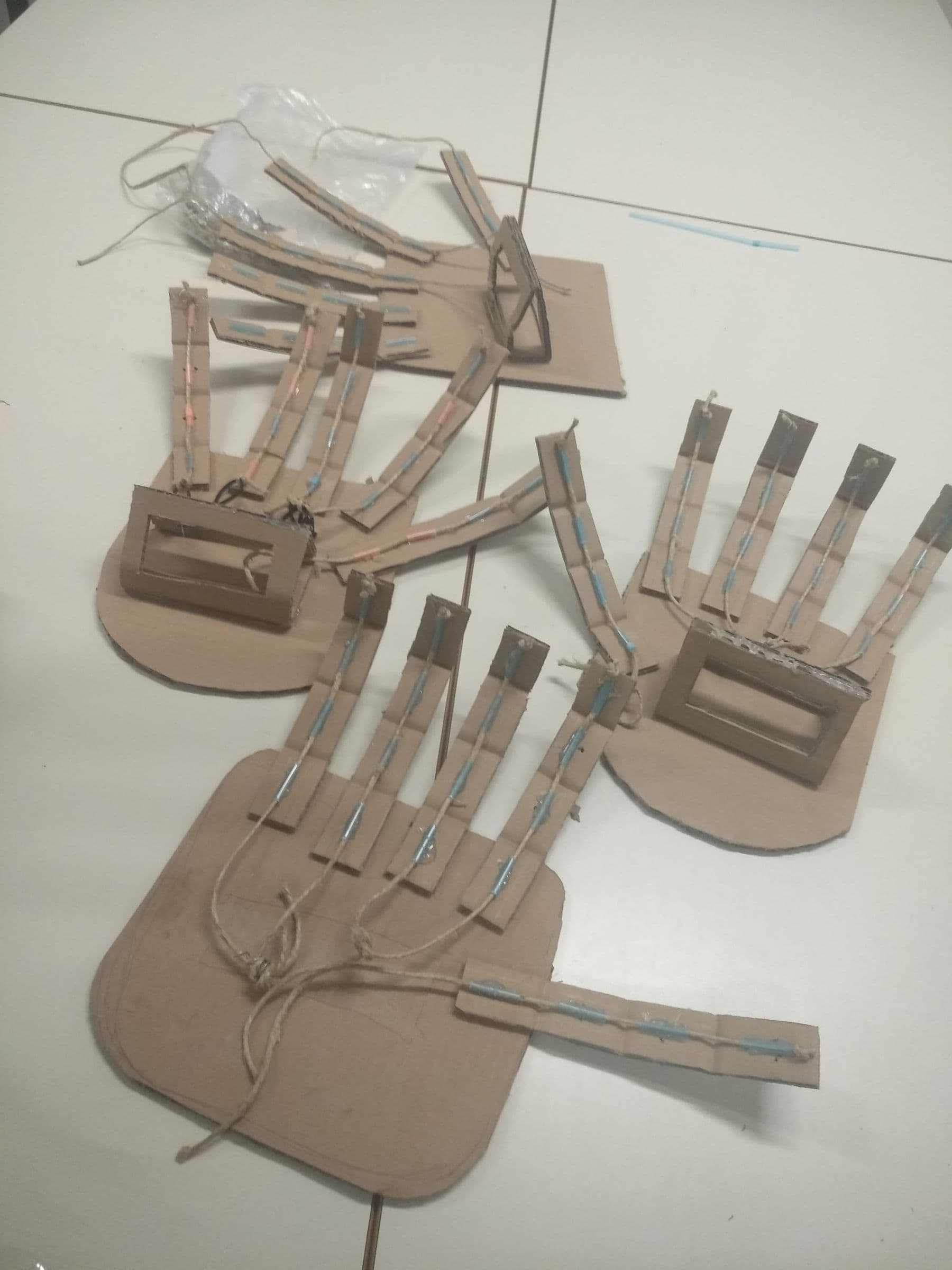 Three cardboard robotic hands with string tendons, a simple DIY robot for kids