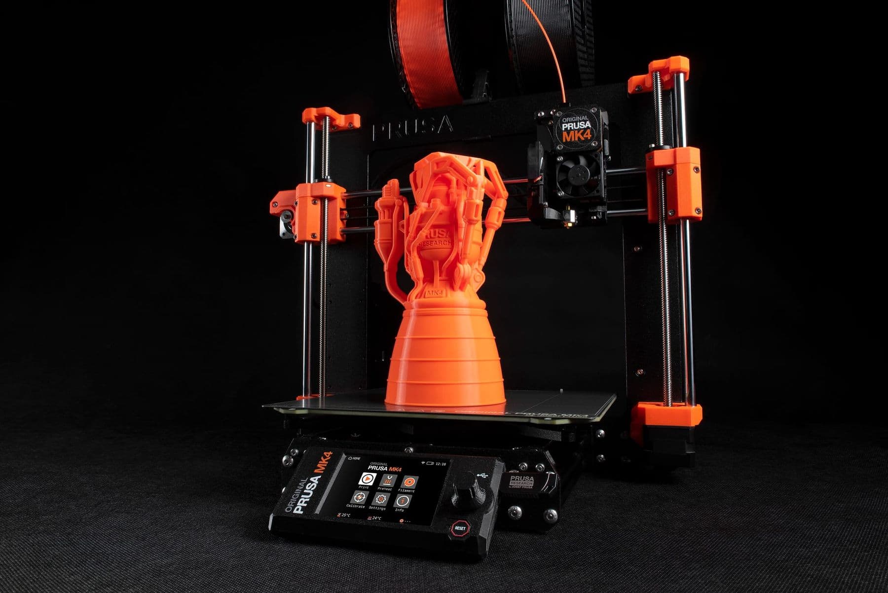 Prusa MK4 3D პრინტერი ნარინჯისფერი დაბეჭდილი მოდელით შავ ფონზე